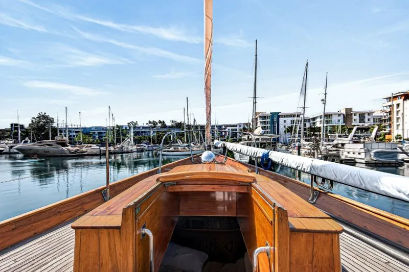 Slide: The Image of 1961 Vic Franck Custom yacht docked in a marina, surrounded by modern buildings and sailboats. - 26