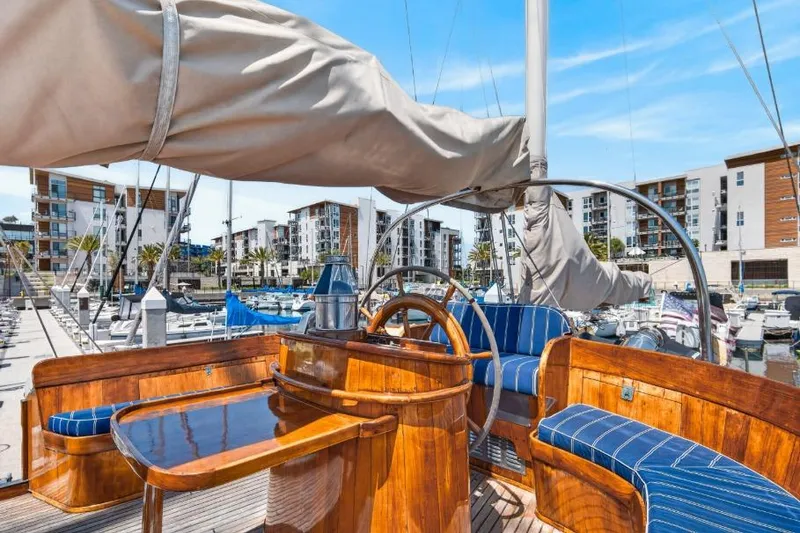 Slide: The Image of 1961 Vic Franck Custom yacht with wooden deck and blue-striped seating in a marina. - 27