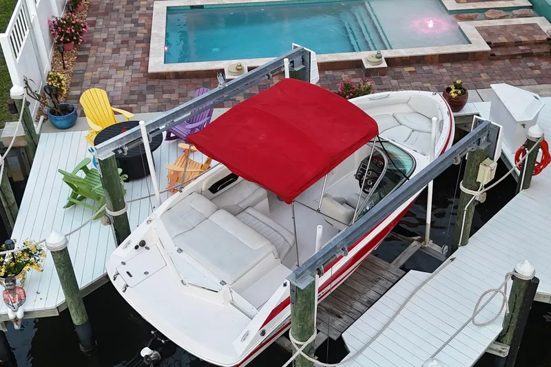 Slide: The Image of 2004 Regal 2000 Bowrider with red canopy docked near a poolside patio. - 11