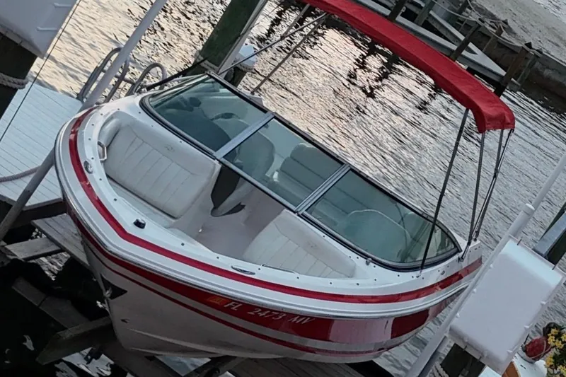 Slide: The Image of 2004 Regal 2000 Bowrider boat with red canopy docked by the water. - 15