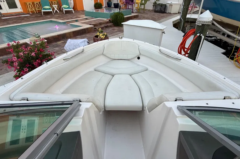 Slide: The Image of 2004 Regal 2000 Bowrider boat interior with white seating, docked near a poolside patio. - 23