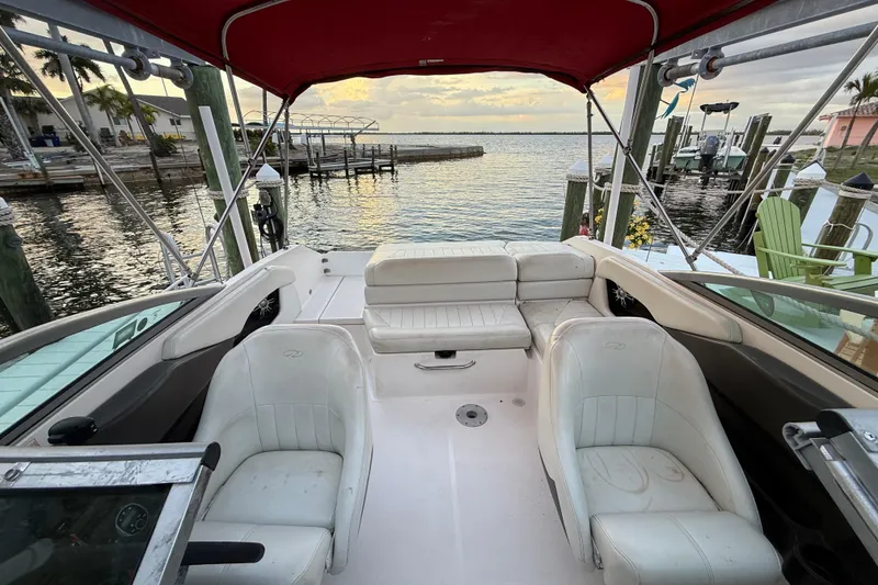 Slide: The Image of 2004 Regal 2000 Bowrider boat interior with white seating and red canopy at dockside. - 24