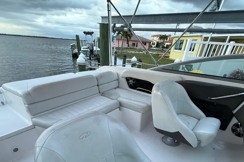Slide: The Image of 2004 Regal 2000 Bowrider boat interior with white seating, docked by waterfront homes. - 25