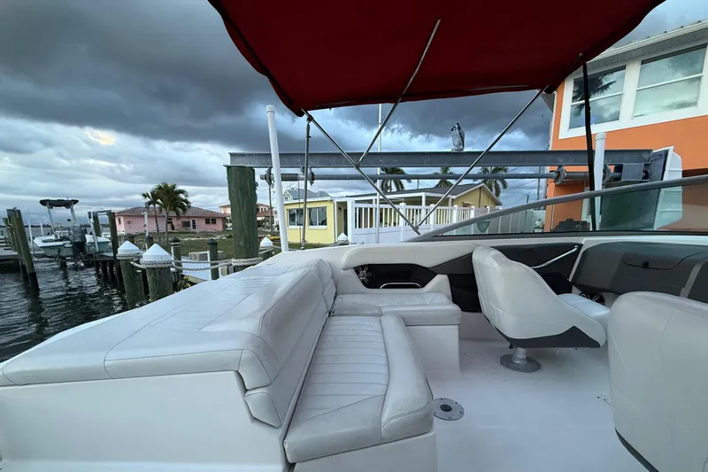 Slide: The Image of 2004 Regal 2000 Bowrider boat interior with white seating and red canopy at dock. - 26