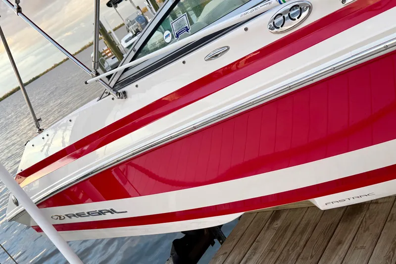 Slide: The Image of 2004 Regal 2000 Bowrider boat with red and white design docked by the water. - 3