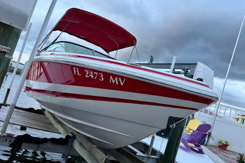 Slide: The Image of Red and white 2004 Regal 2000 Bowrider boat docked, featuring a canopy and registration number. - 5