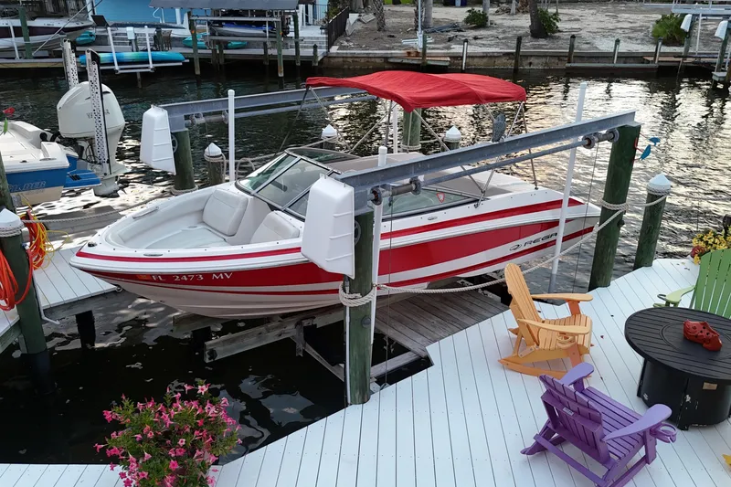 Slide: The Image of 2004 Regal 2000 Bowrider boat docked with colorful chairs on a waterfront deck. - 6