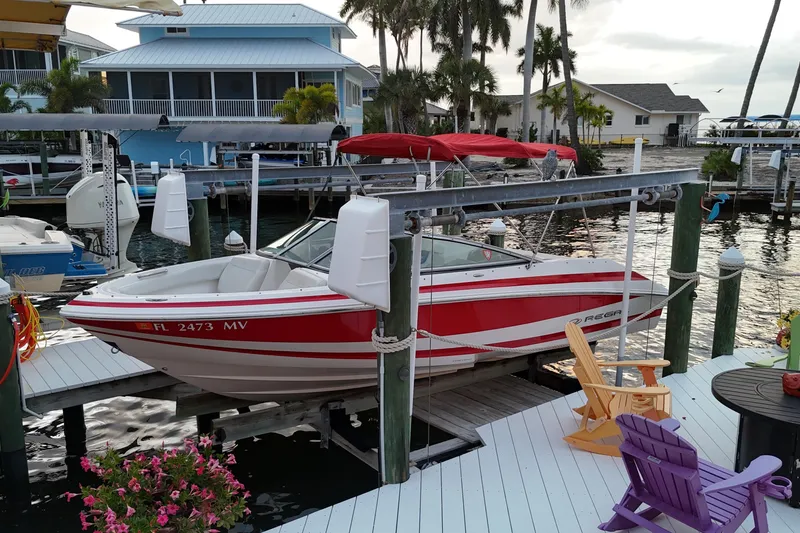 Slide: The Image of 2004 Regal 2000 Bowrider boat docked at a marina with colorful chairs nearby. - 8