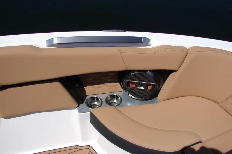 Slide: The Image of 2021 MasterCraft X26 boat interior with tan seating, cup holders, and speaker. - 14