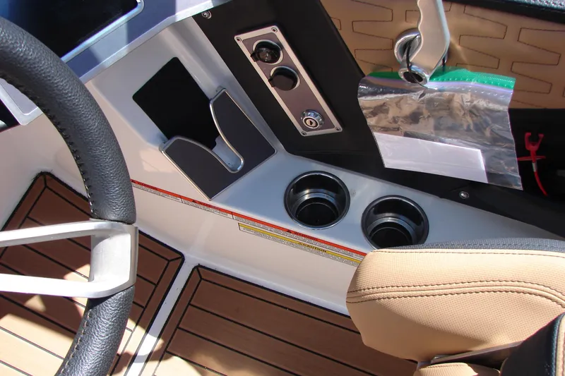 Slide: The Image of 2021 MasterCraft X26 boat interior with steering wheel, cup holders, and control panel. - 16