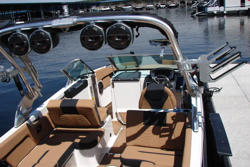 Slide: The Image of 2021 MasterCraft X26 boat interior with brown seating and audio system at a dock. - 17