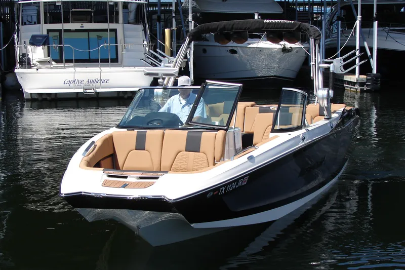 Slide: The Image of 2021 MasterCraft X26 boat with tan seating, docked in a marina. - 2