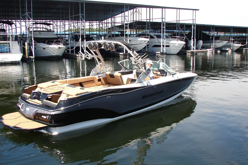 Slide: The Image of 2021 MasterCraft X26 boat docked at marina with luxury yachts in background. - 6