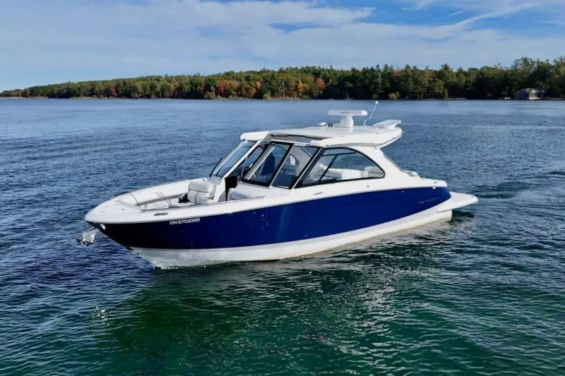 The Image of 2025 Regal LS36 boat cruising on a serene lake with forested shoreline. - 0