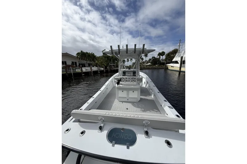 Slide: The Image of 2015 Conch 27 boat docked, featuring spacious deck and modern design under cloudy sky. - 20