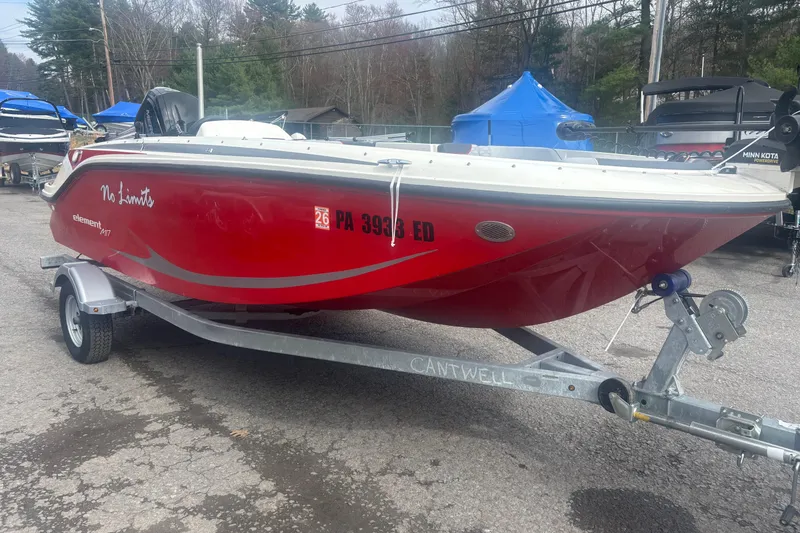 Slide: The Image of 2023 Bayliner Element E17 boat in red on a trailer, parked outdoors. - 5