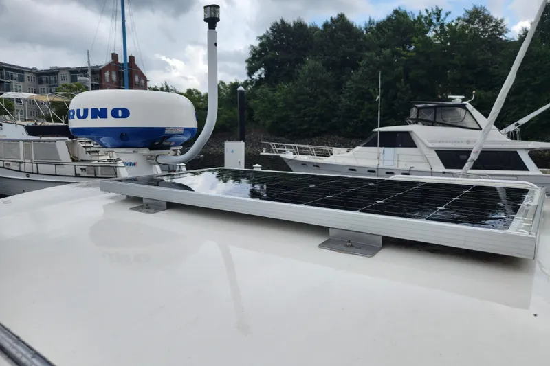 Slide: The Image of Boat with solar panel and radar system docked at marina, surrounded by trees and buildings. - 5