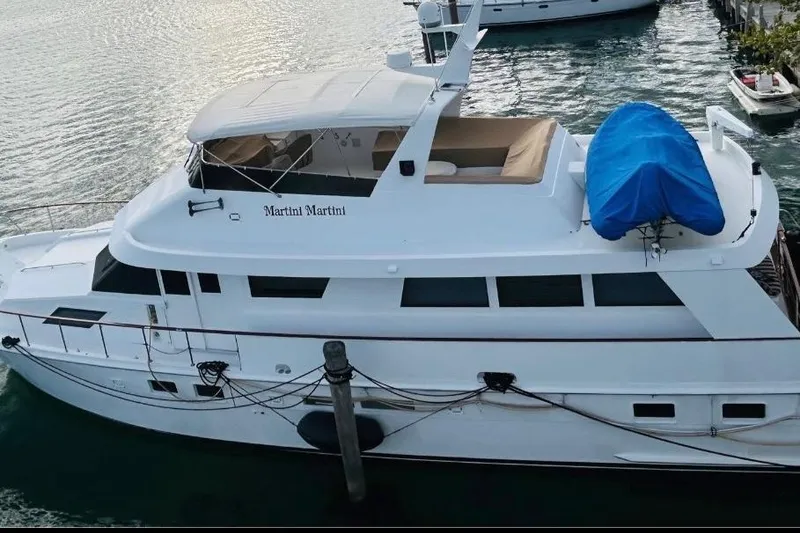 Slide: The Image of 1991 Hatteras 70 Cockpit Motor Yacht docked, featuring sleek design and spacious deck. - 1