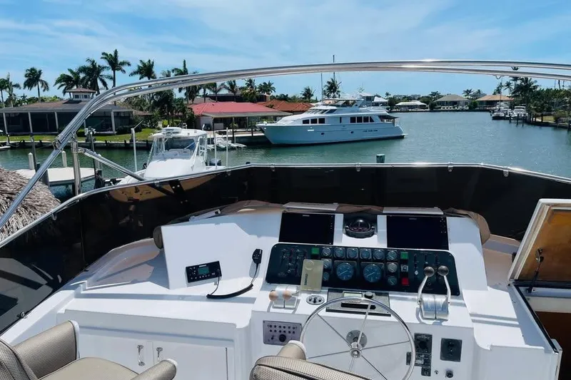 Slide: The Image of Cockpit view of 1991 Hatteras 70 Cockpit Motor Yacht, docked in a scenic marina. - 20