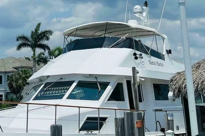 Slide: The Image of 1991 Hatteras 70 Cockpit Motor Yacht docked, featuring sleek design and spacious upper deck. - 23
