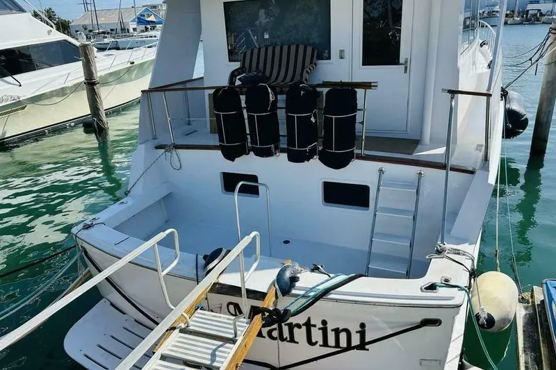 Slide: The Image of 1991 Hatteras 70 Cockpit Motor Yacht docked, featuring spacious deck and ladder access. - 25
