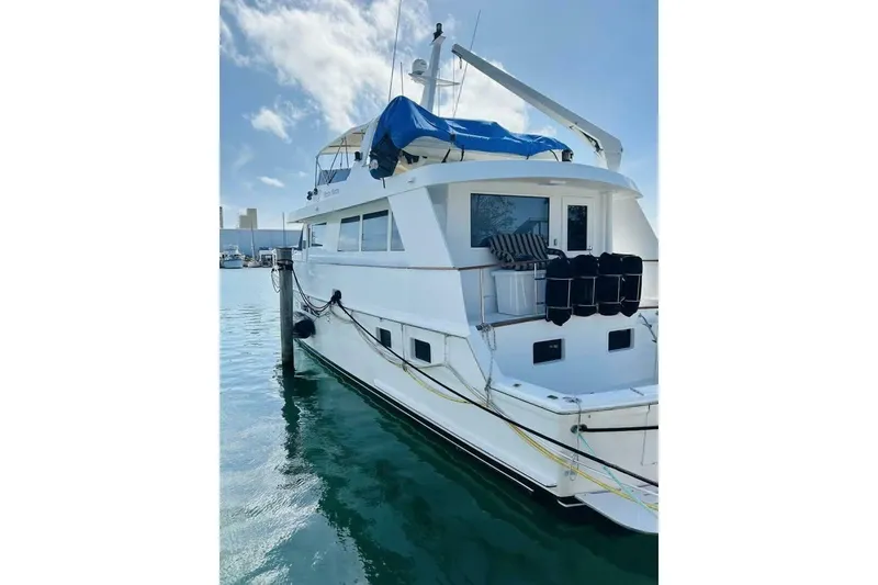 Slide: The Image of 1991 Hatteras 70 Cockpit Motor Yacht docked in calm waters under a blue sky. - 26