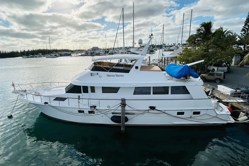 Slide: The Image of 1991 Hatteras 70 Cockpit Motor Yacht docked at a marina under a cloudy sky. - 3