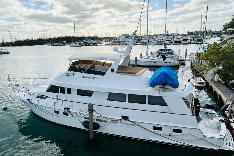 Slide: The Image of 1991 Hatteras 70 Cockpit Motor Yacht docked in a marina under cloudy skies. - 4