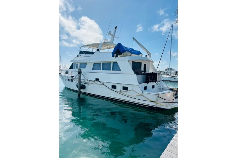 Slide: The Image of 1991 Hatteras 70 Cockpit Motor Yacht docked in clear blue water. - 5