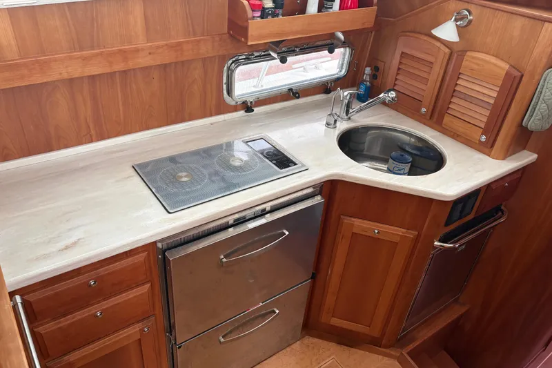 Slide: The Image of 2020 Sabre 42 Salon Express galley with stove, sink, and wooden cabinetry. - 6