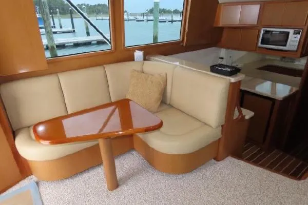 Slide: The Image of Henriques 42 Flybridge 2011 interior with beige seating, wooden table, and kitchenette. - 6