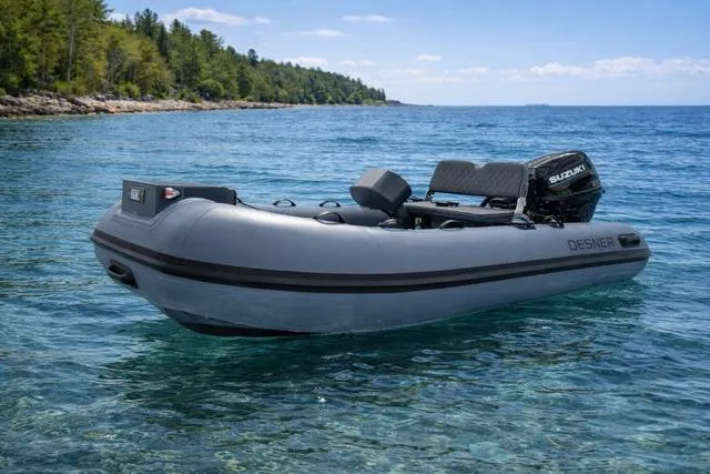 Slide: The Image of 2026 Desner CL 360 FCT inflatable boat on clear blue water near a forested shoreline. - 3
