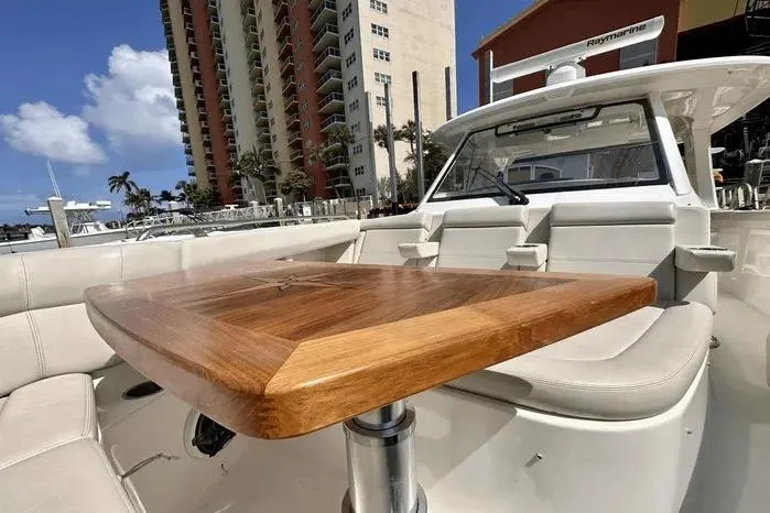 Slide: The Image of 2019 Boston Whaler 350 Realm boat interior with wooden table and seating. - 10
