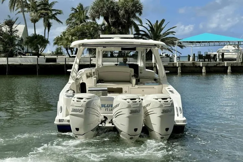 Slide: The Image of 2019 Boston Whaler 350 Realm boat with triple Mercury engines in a scenic marina. - 3