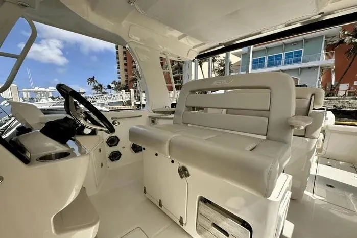 Slide: The Image of 2019 Boston Whaler 350 Realm interior with helm and seating, dockside view. - 6