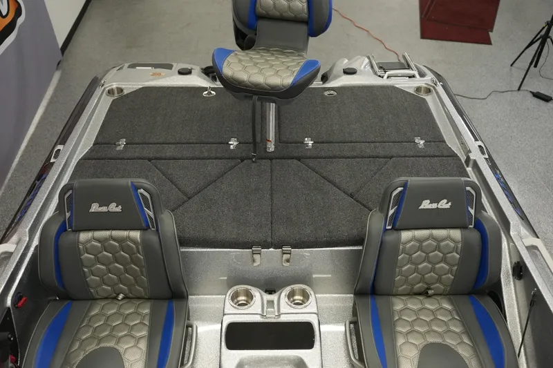 Slide: The Image of 2026 Bass Cat Lynx STS boat interior with gray and blue seating, featuring cup holders and storage. - 14