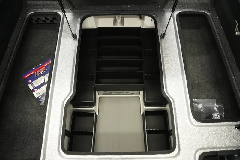 Slide: The Image of 2026 Bass Cat Lynx STS boat storage compartment with organized tackle boxes and accessories. - 20