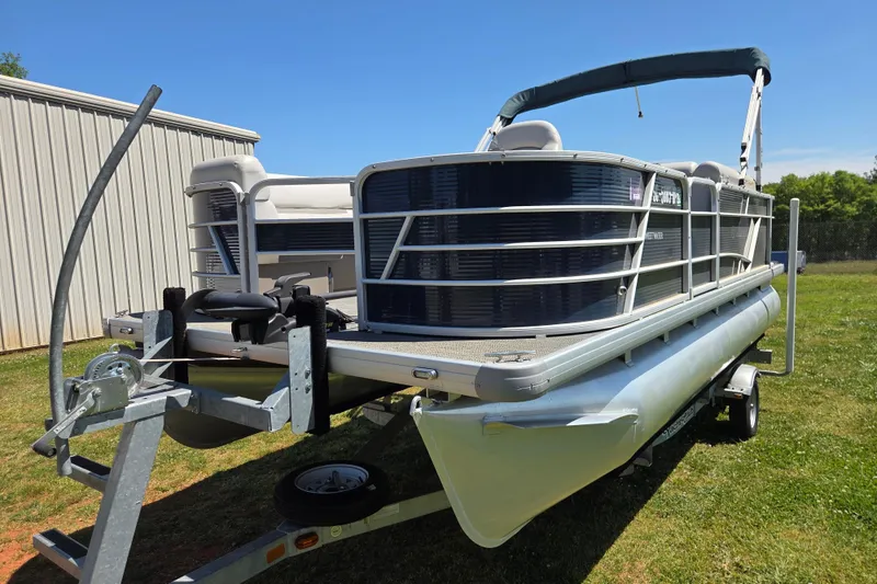 Slide: The Image of 2021 Godfrey Sweetwater 1880 FX pontoon boat on trailer, parked on grass. - 1
