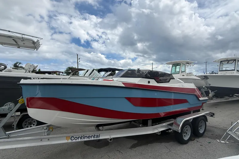 The Image of Custom DW DESIGN 570BR 2025 boat on trailer, blue and red color scheme, cloudy sky background. - 1