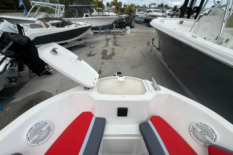 Slide: The Image of Custom DW DESIGN 570BR boat, 2025 model, with red and gray seating, docked among other boats. - 12