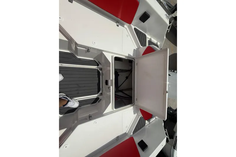 Slide: The Image of Open storage compartment on Custom DW DESIGN 570BR boat, featuring red and white interior, 2025 model. - 21