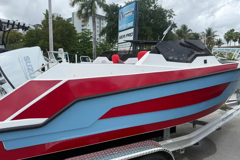 Slide: The Image of Custom DW DESIGN 570BR 2025 boat with red and blue accents on a trailer. - 3