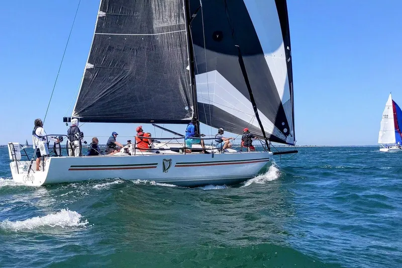 Slide: The Image of 2018 J Boats J/121 sailing on open water with crew, featuring black sails. - 3
