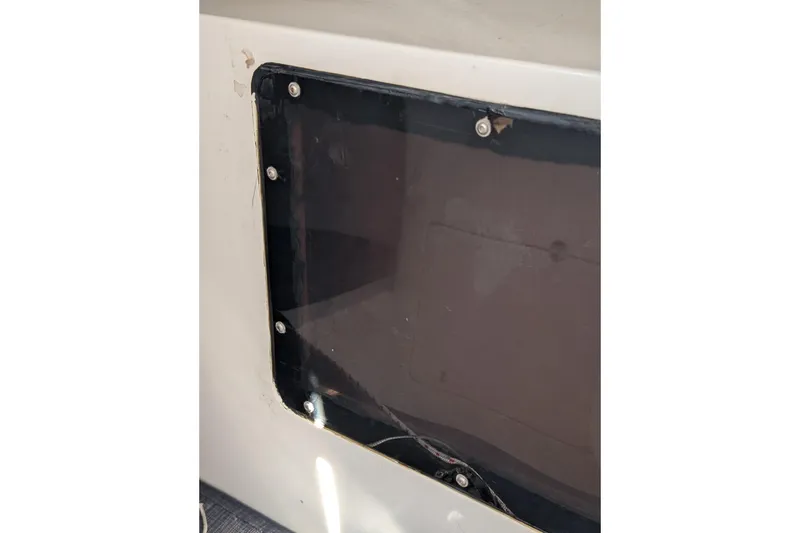 Slide: The Image of Close-up of a 2018 J Boats J/121 window with visible screws and frame. - 33