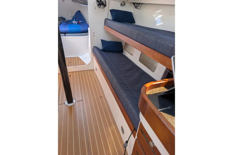 Slide: The Image of Interior of 2018 J Boats J/121 sailboat with wooden flooring and blue cushioned bunks. - 19