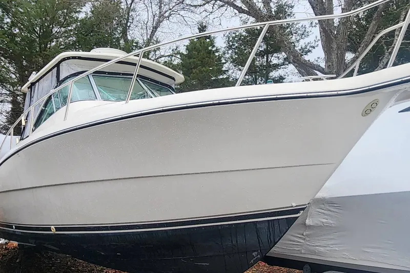 The Image of 2003 Pursuit 3070 Express boat on land, surrounded by trees. - 0