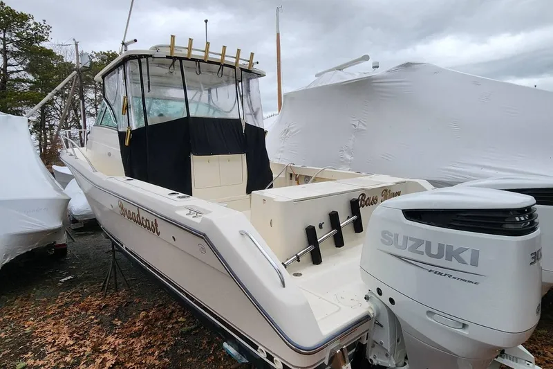 Slide: The Image of 2003 Pursuit 3070 Express boat with Suzuki outboard motor, docked outdoors. - 1