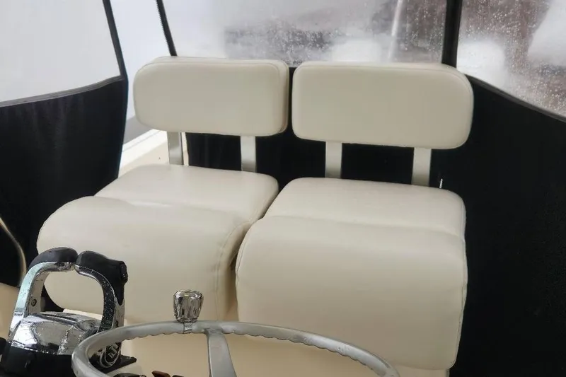 Slide: The Image of 2003 Pursuit 3070 Express boat interior with white cushioned seats and steering wheel. - 10