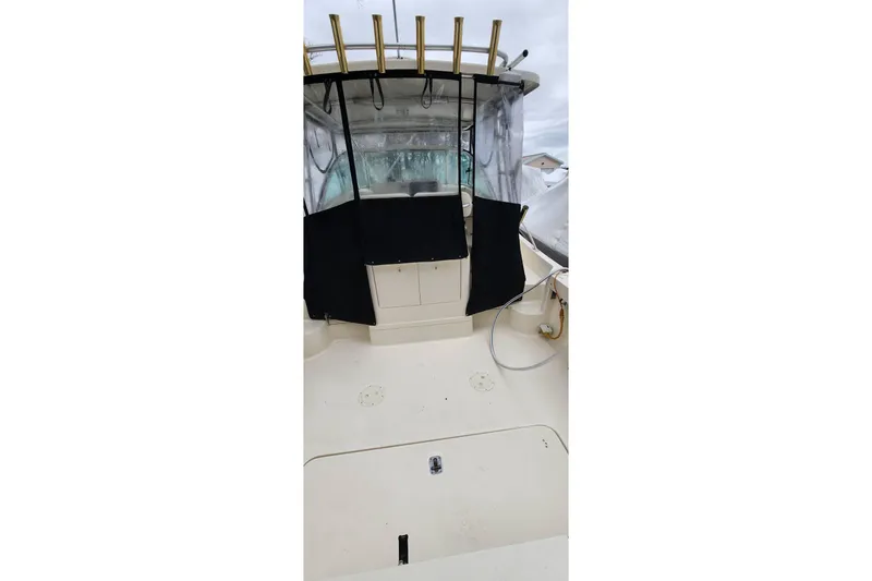 Slide: The Image of 2003 Pursuit 3070 Express boat deck with rod holders and enclosed cockpit. - 11