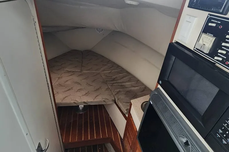 Slide: The Image of 2003 Pursuit 3070 Express cabin interior with bed, microwave, and control panel. - 17